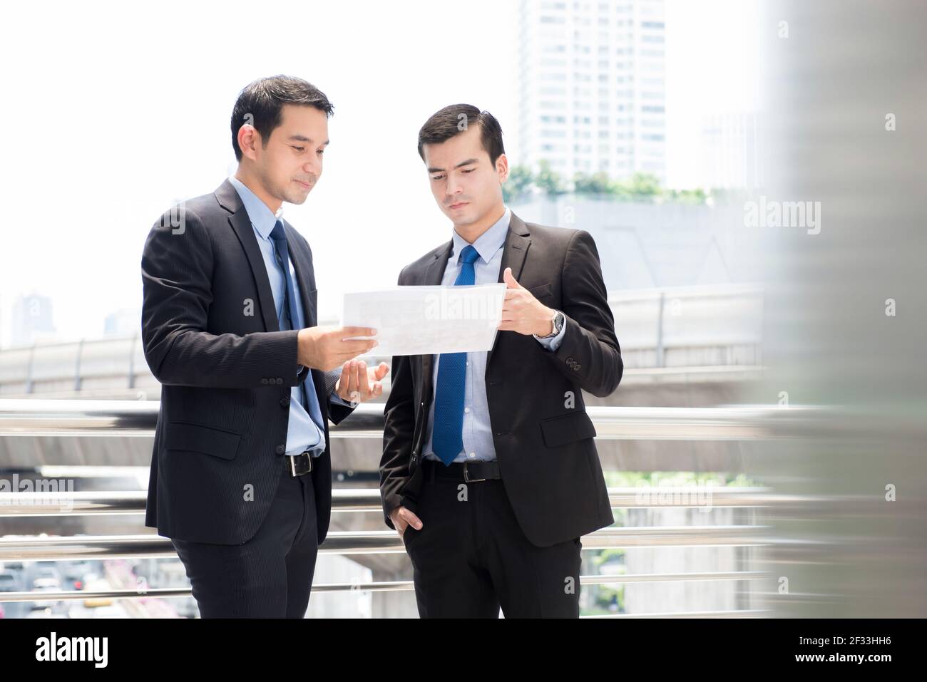 Zwei Geschäftsleute als Kollegen diskutieren Dokument im Freien Stockfoto