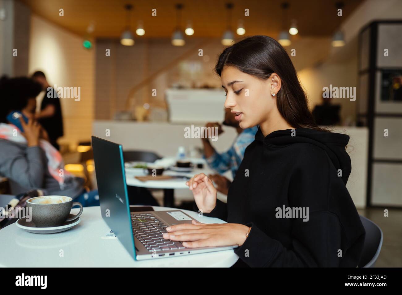 Portrait einer Studentin, die im Café mit einem Netzbuch sitzt Stockfoto