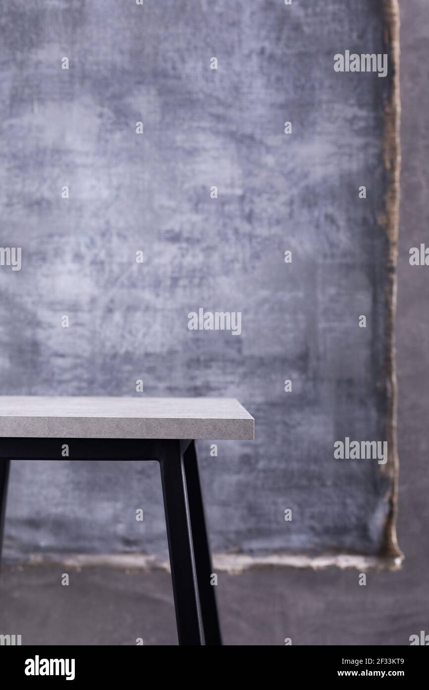 Tisch oder Metall Hocker und abstrakt bemalte Leinwand in der Nähe Betonwand Hintergrund. Tischplatte oder Ablage Stockfoto