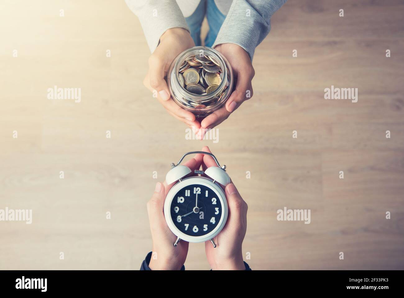 Hände, die Geld halten, tauschen sich mit Zeit, Geschäft und finanzieller Metapher aus Stockfoto