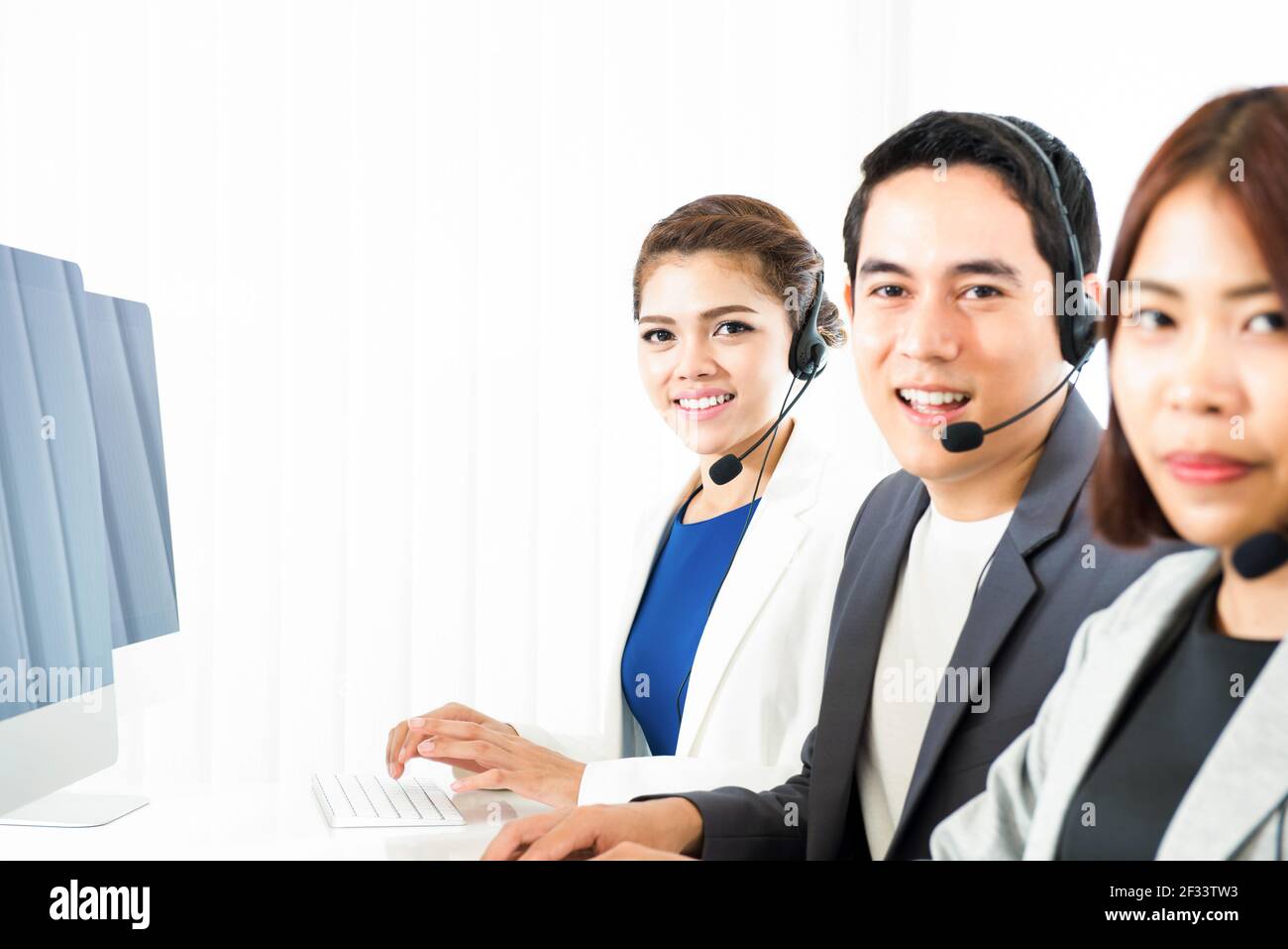 Lächelndes asiatisches Call Center (oder Telemarketingteam) Stockfoto