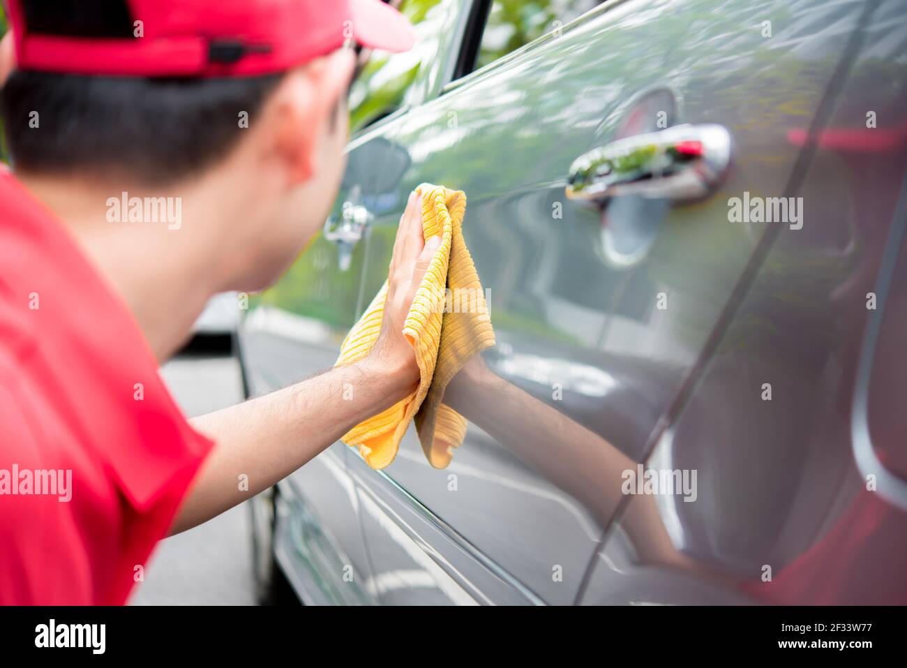 Ein Mann Reinigung Auto mit Mikrofaser Tuch - Auto-Reinigung Servicekonzept Stockfoto