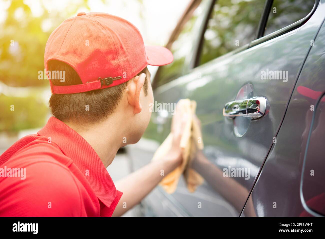 Ein Mann in roten Uniform Reinigung Auto - Auto Reinigung Servicekonzept Stockfoto