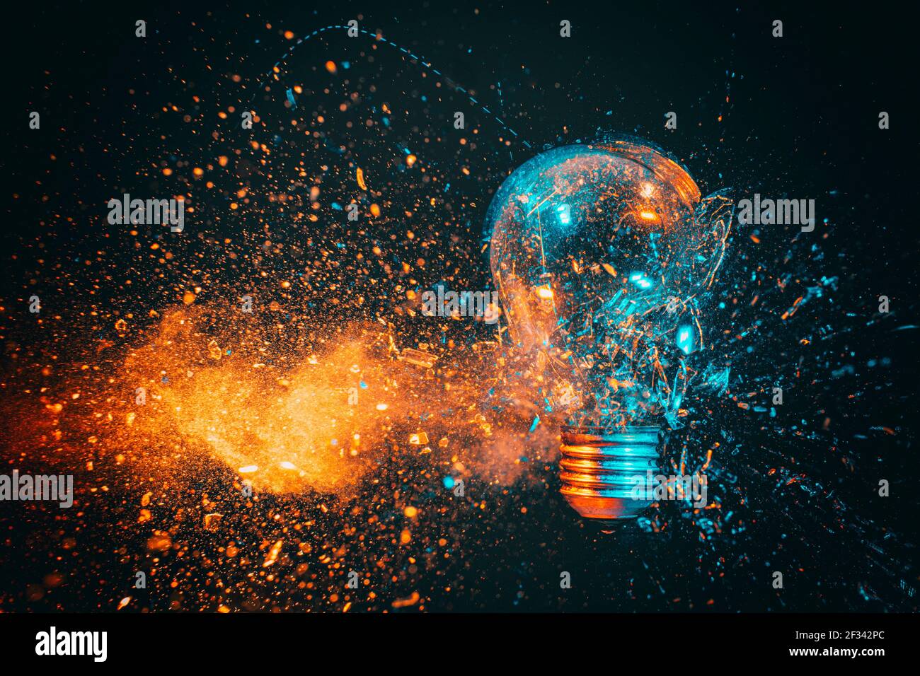 Explosion einer Glühbirne. Schwarzer Hintergrund und blaue und orange Töne. High-Speed-Fotografie. Stockfoto