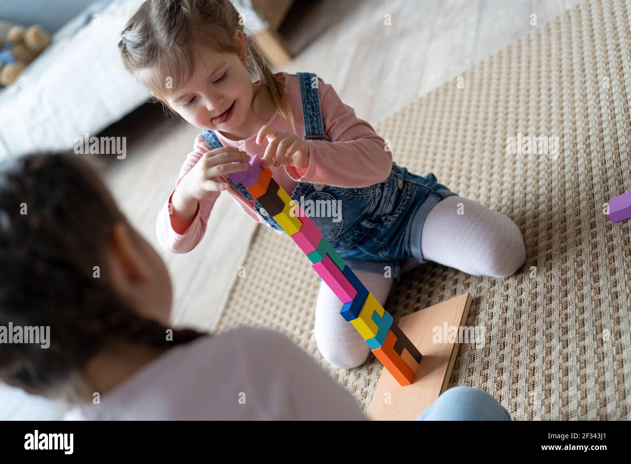Kinder spielen mit Holzblöcken, die auf dem Boden in ihrem Zimmer liegen. Stockfoto