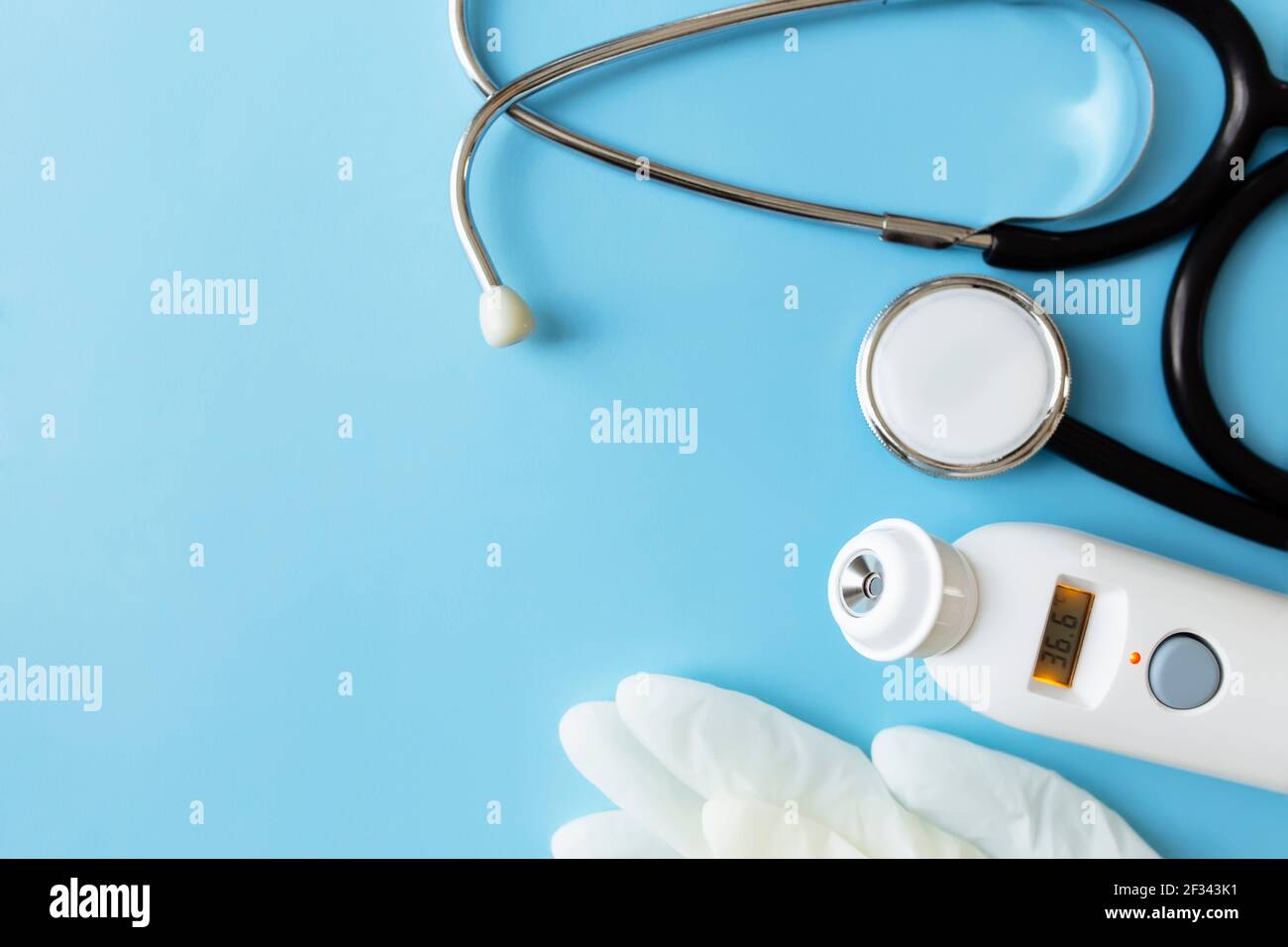 Behandlungskonzept der Medizin. Elektronisches Thermometer, Phonendoskop oder Stethoskop, weiße Handschuhe auf blauem Hintergrund. Hochwertige Fotos Stockfoto