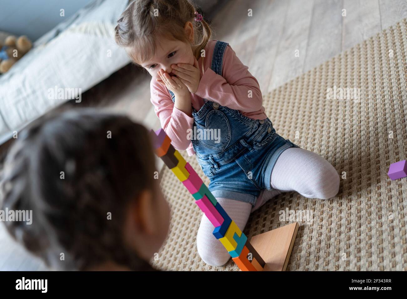Kinder spielen mit Holzblöcken, die auf dem Boden in ihrem Zimmer liegen. Stockfoto