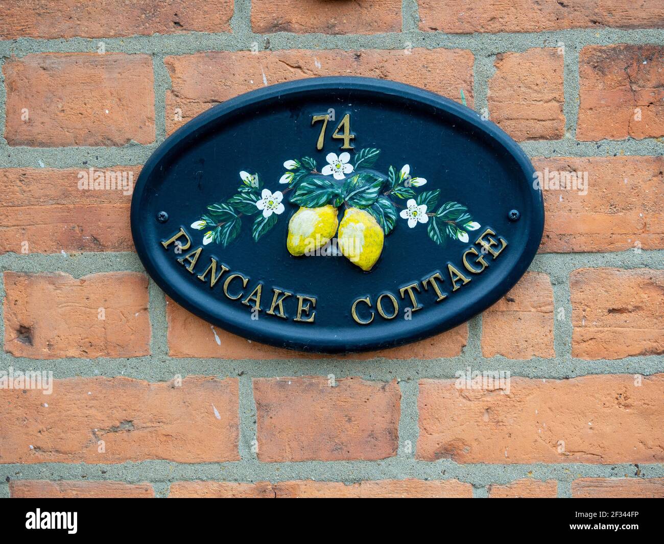 Ovale Metall Wand montiert Haus Schild für Pancake Cottage, Olney, Buckinghamshire; bezieht sich auf die berühmte Pancake Rennen, die in der Stadt stattfindet. Stockfoto