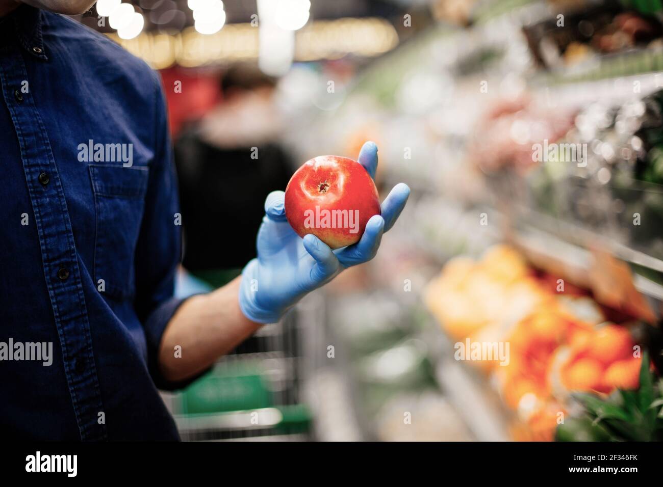 Frischer Apfel in den Händen eines Mannes in Schutzhandschuhen Stockfoto