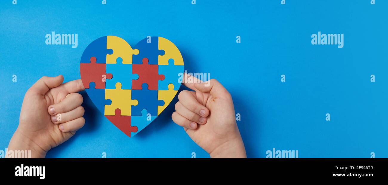 Autistische junge Hände halten Puzzle Herz Form. Autismus-Spektrum-Störung Familie Unterstützungskonzept. Welt Autismus Awareness Day Stockfoto