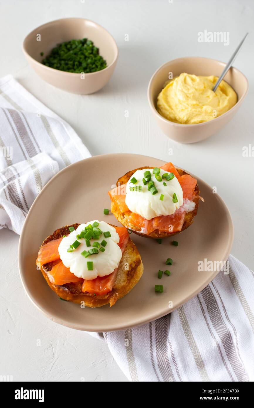 Leckeres herzhaftes Frühstück, Eier Atlantic in einem Teller auf weißem Hintergrund, Runde gebratene Brötchen mit Lachs und Eier Benedikt, Sauce Hollandaise Stockfoto
