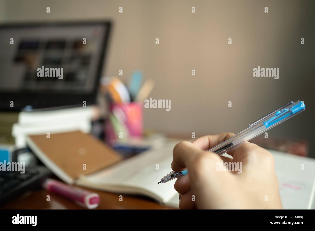 Kreatives Denkkonzept. Ein Stift in der Hand mit einem unordentlichen Arbeitstisch im Hintergrund. Stockfoto