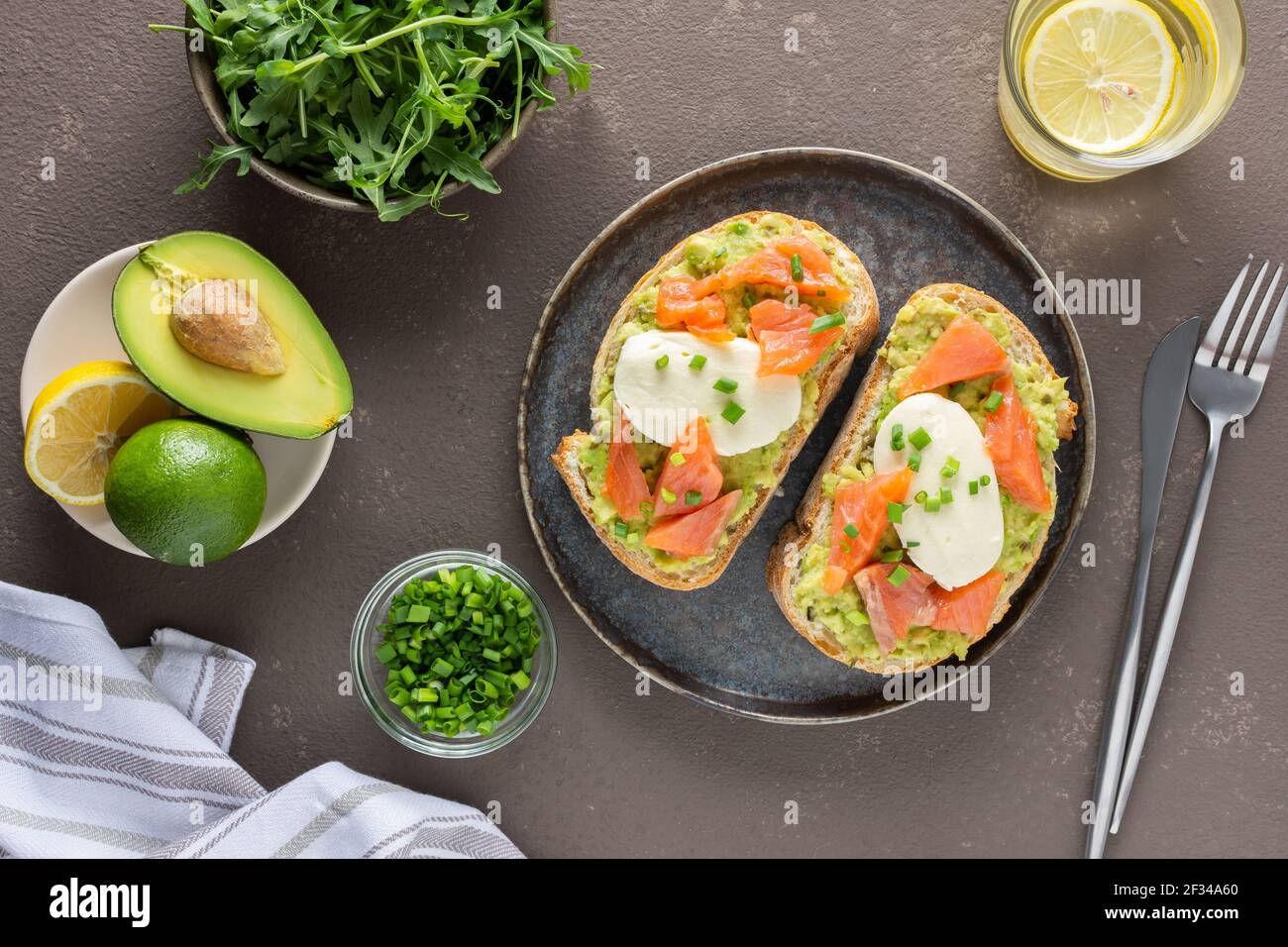 Leckeres herzhaftes Frühstück, Sandwiches mit Avocado-Paste, Lachs und Mozzarella auf einem Teller, Rucola und Erbsensprossen und grüne Zwiebel Stockfoto