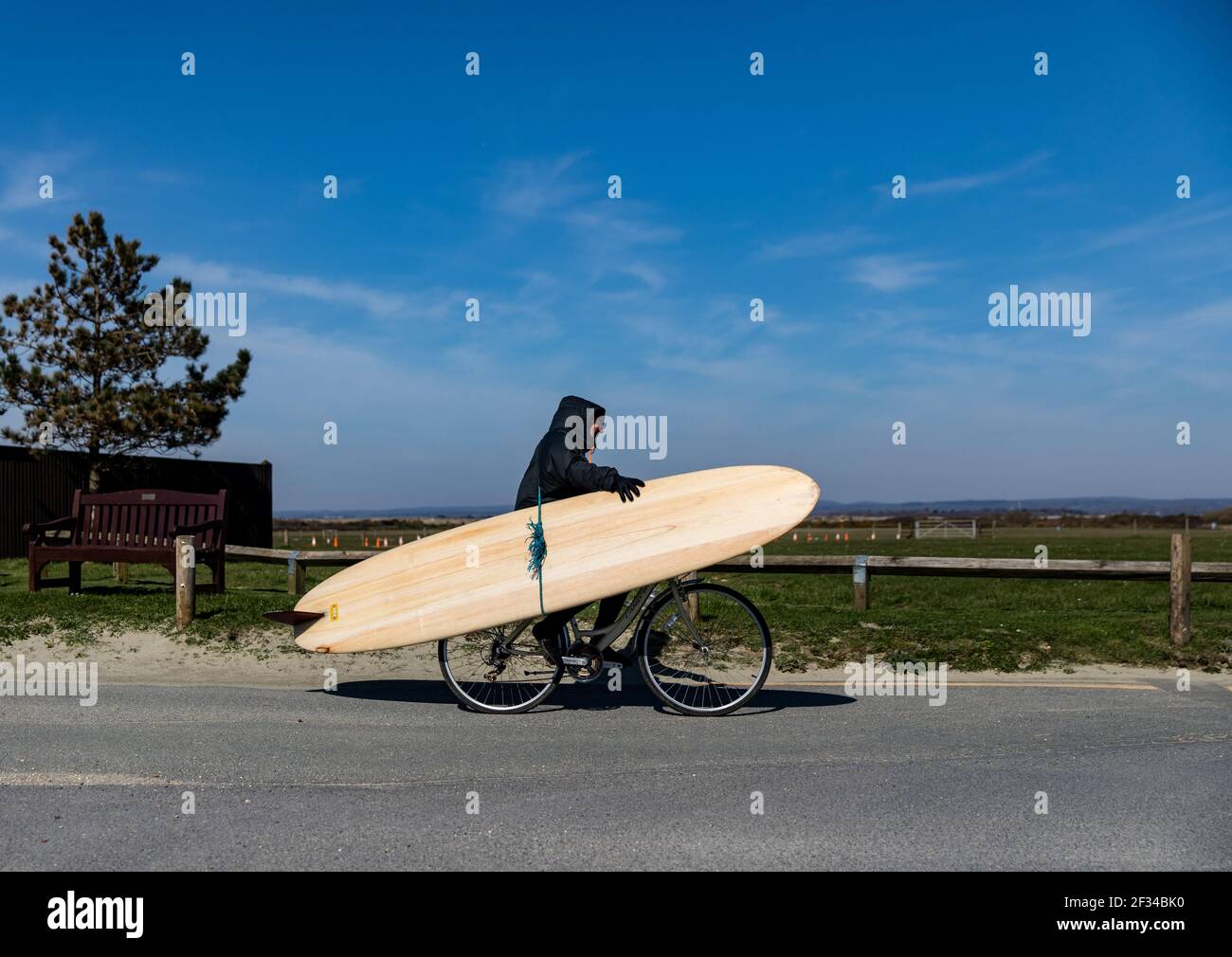 Ein lokaler Surfer, der den West Wittering Beach verlässt, hält sich in sozialer Distanz, da der Parkplatz geschlossen werden muss, nachdem Tausende von Menschen am Satur auftauchten Stockfoto