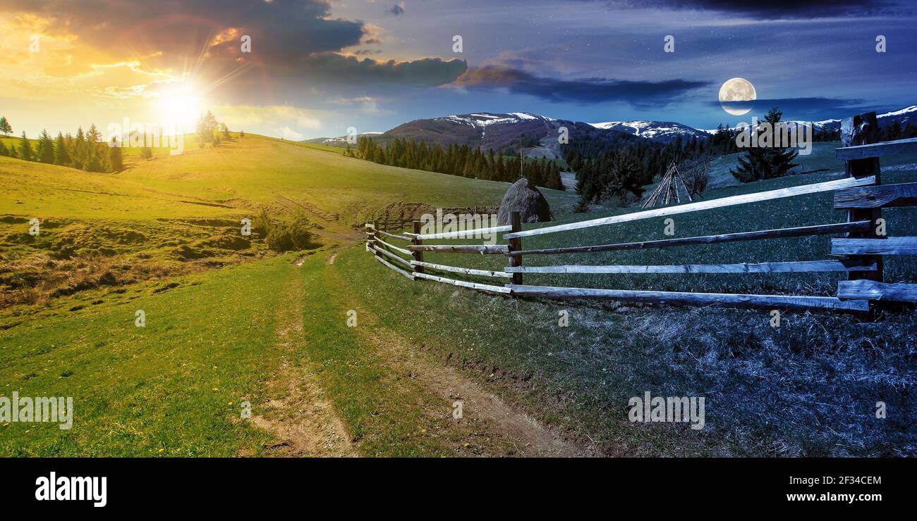 Tag und Nacht ändern Konzept über ländliche Landschaft im Frühjahr. Weg durch Grasfeld. Holzzaun auf sanften Hügeln. Schneebedeckten Bergrücken in der Stockfoto