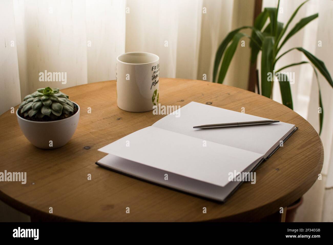 Minimalistischer Arbeitsplatz zu Hause, mit einer Tasse Kaffee und einem offenen, leeren Notizbuch auf dem Schreibtisch Stockfoto