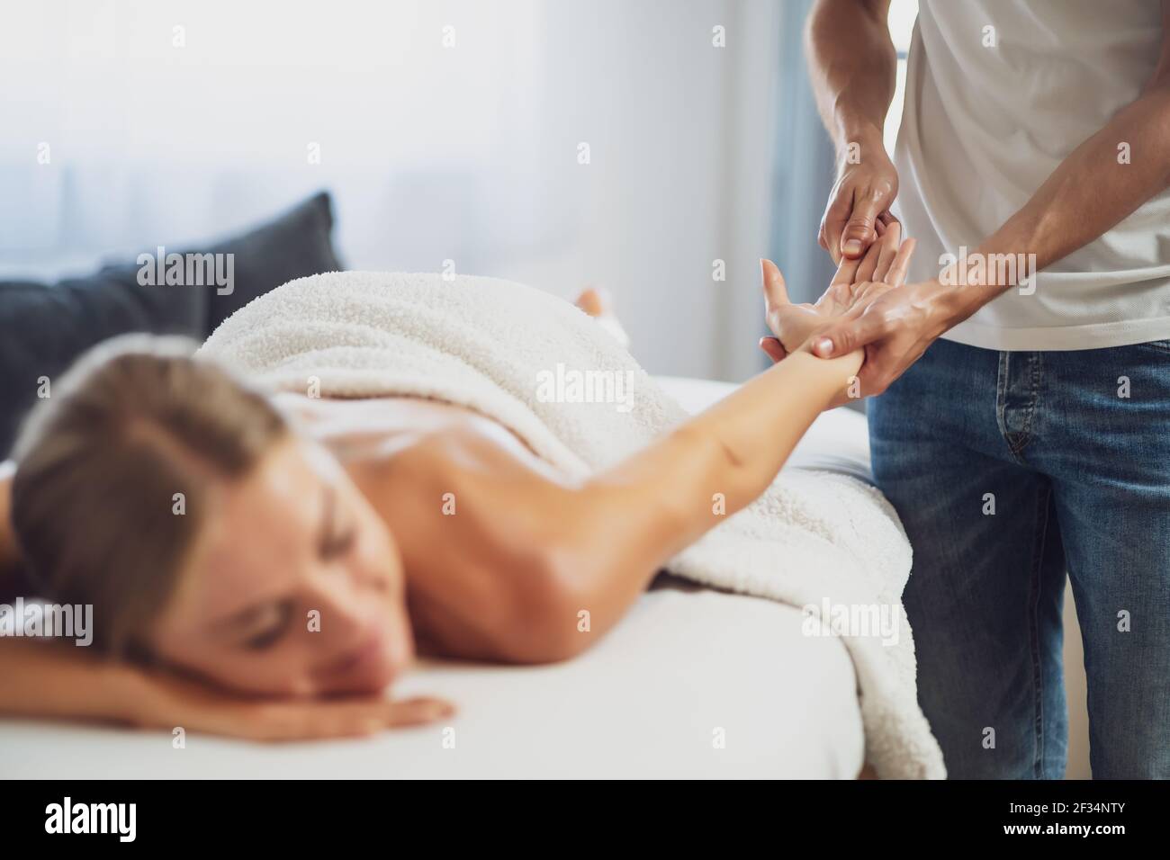 Professionelle Masseur tun therapeutische Massage. Frau genießt Massage in ihrem Haus. Junge Frau bekommen entspannende Körpermassage. Stockfoto
