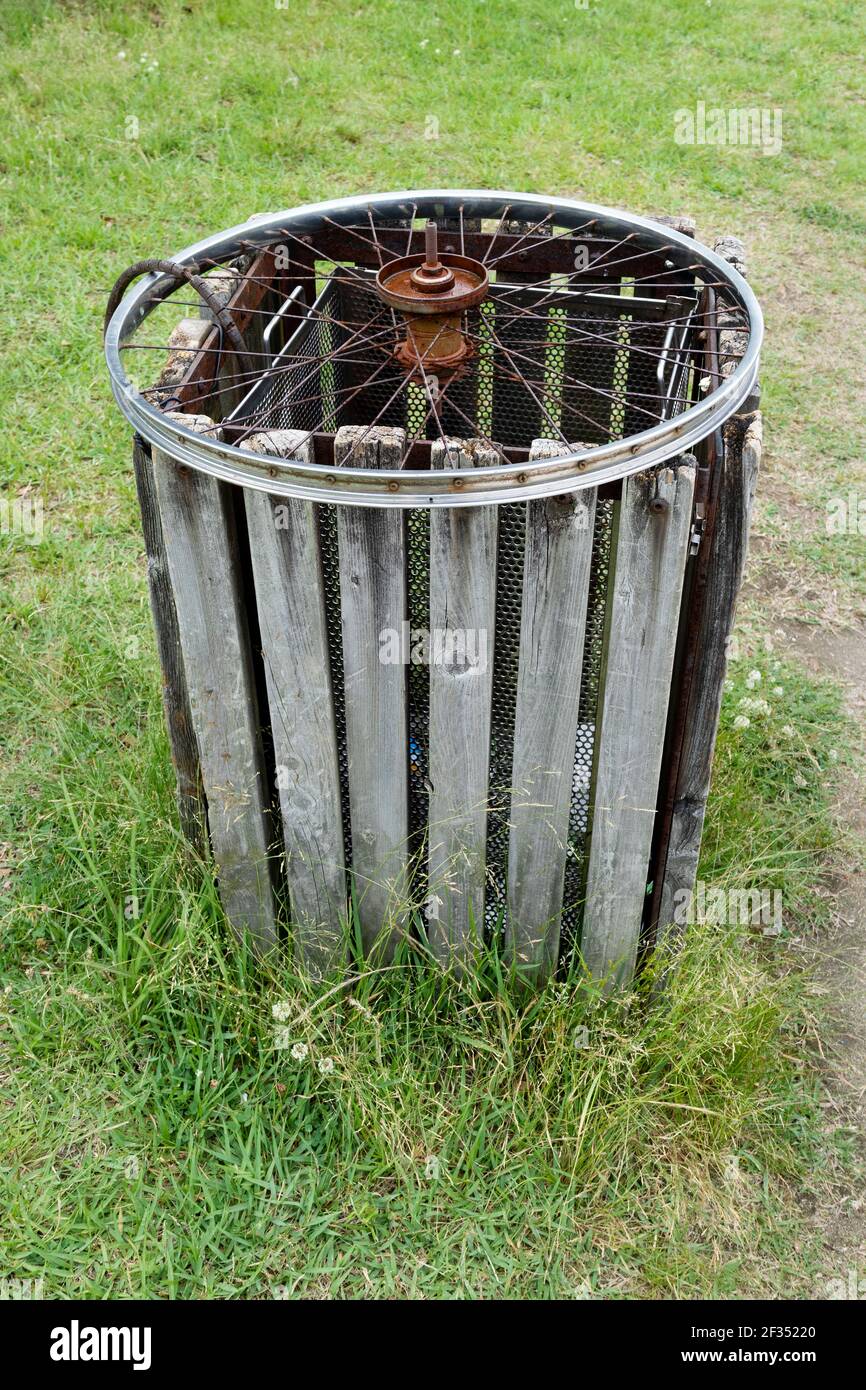 Einfache Idee, ein altes Rad zu recyceln, um ein zu schützen Mülltonne im Park Stockfoto