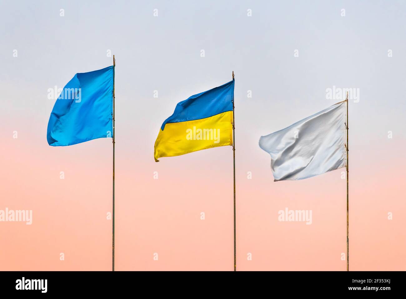 Drei Flaggen: Ukrainische nationale, weiß und blau gegen den Himmel mit einem Farbton des Sonnenuntergangs. Stockfoto