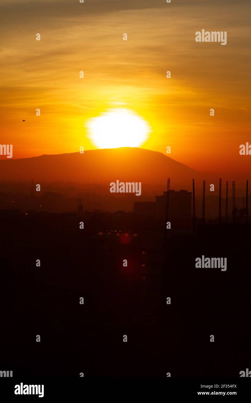 NAIROBI, KENIA - 17. Apr 2020: Die Sonne geht über einem Hügel auf, während die Stadt in Silhoutte liegt Stockfoto