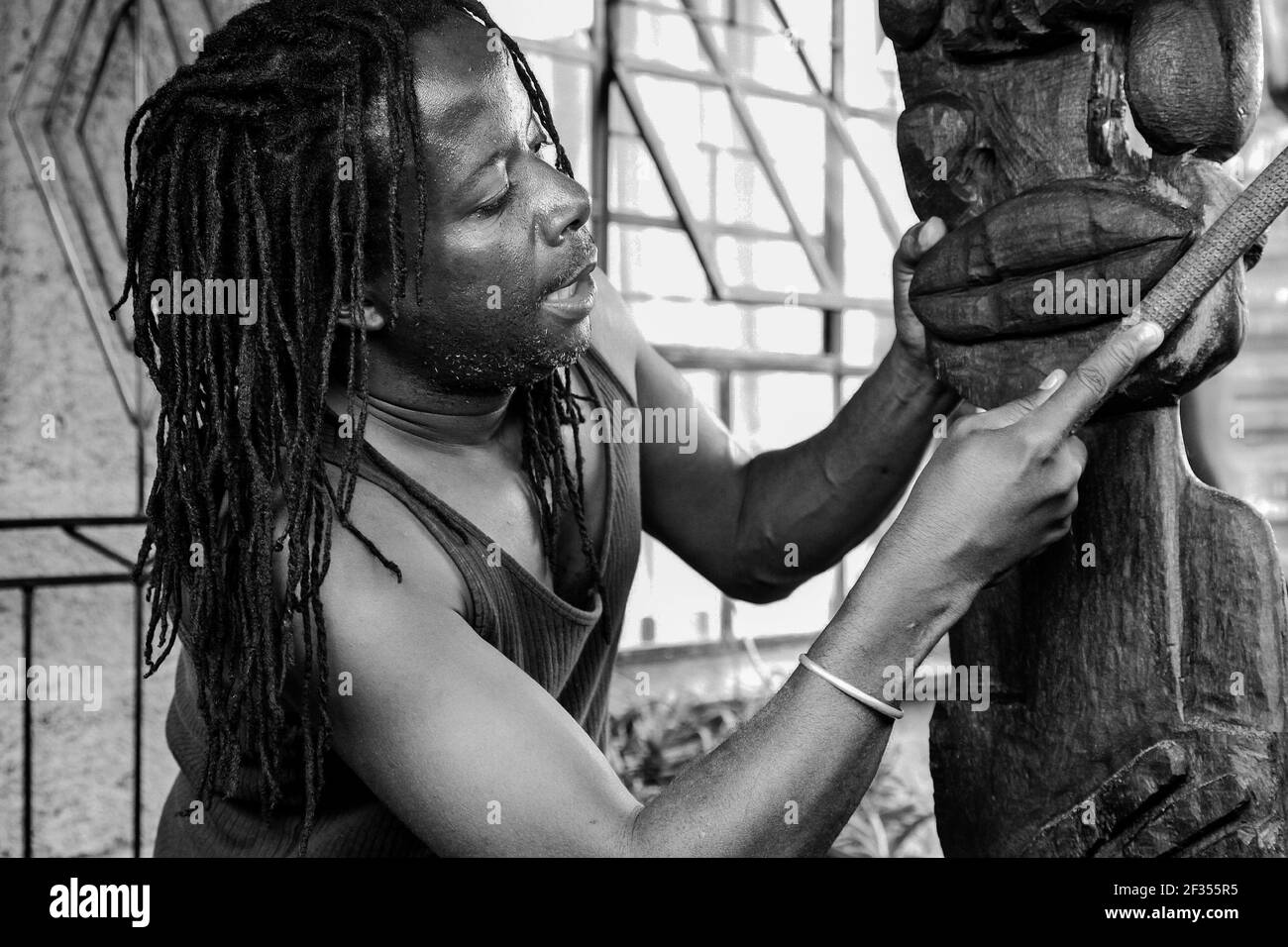 JOHANNESBURG, SÜDAFRIKA - 13. Mär 2021: Johannesburg, Südafrika - 17. Januar 2011: Afrikanischer Mann Bildhauer Schnitzerei eine traditionelle Statue aus woo Stockfoto