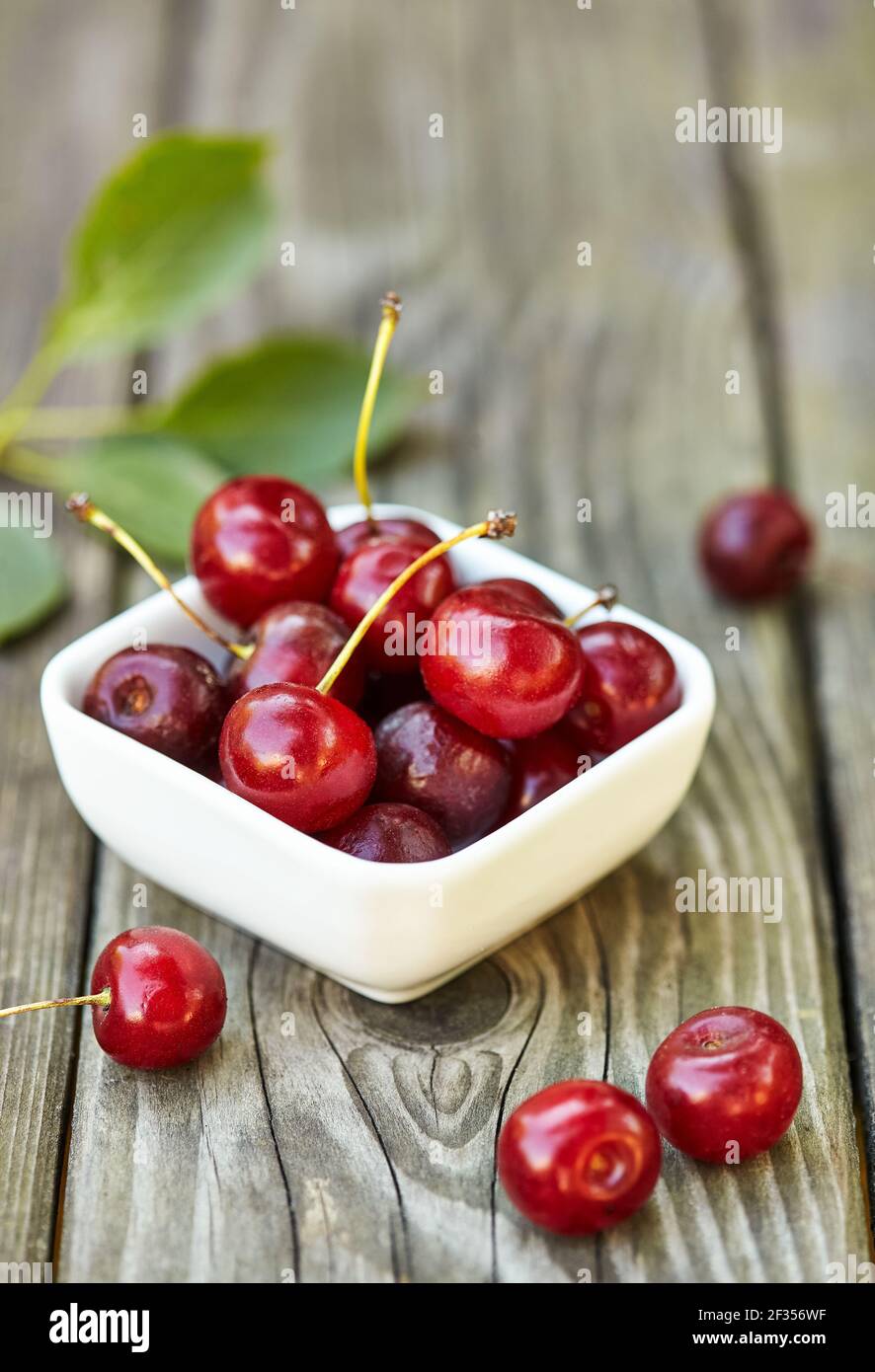 Kirsche in einer Schüssel auf grauem Holztisch. Reife reife reife Kirschen. Süße rote Kirschen. Stockfoto