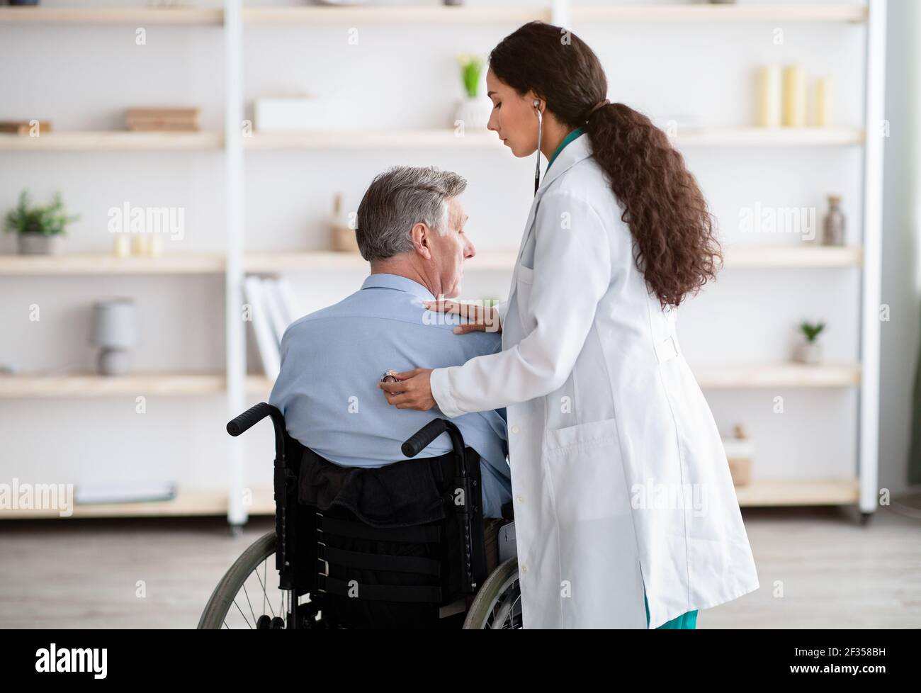 Ältere Patienten mit körperlicher Behinderung erhalten medizinische Hilfe von jungen Menschen Arzt während der covid Epidemie Stockfoto