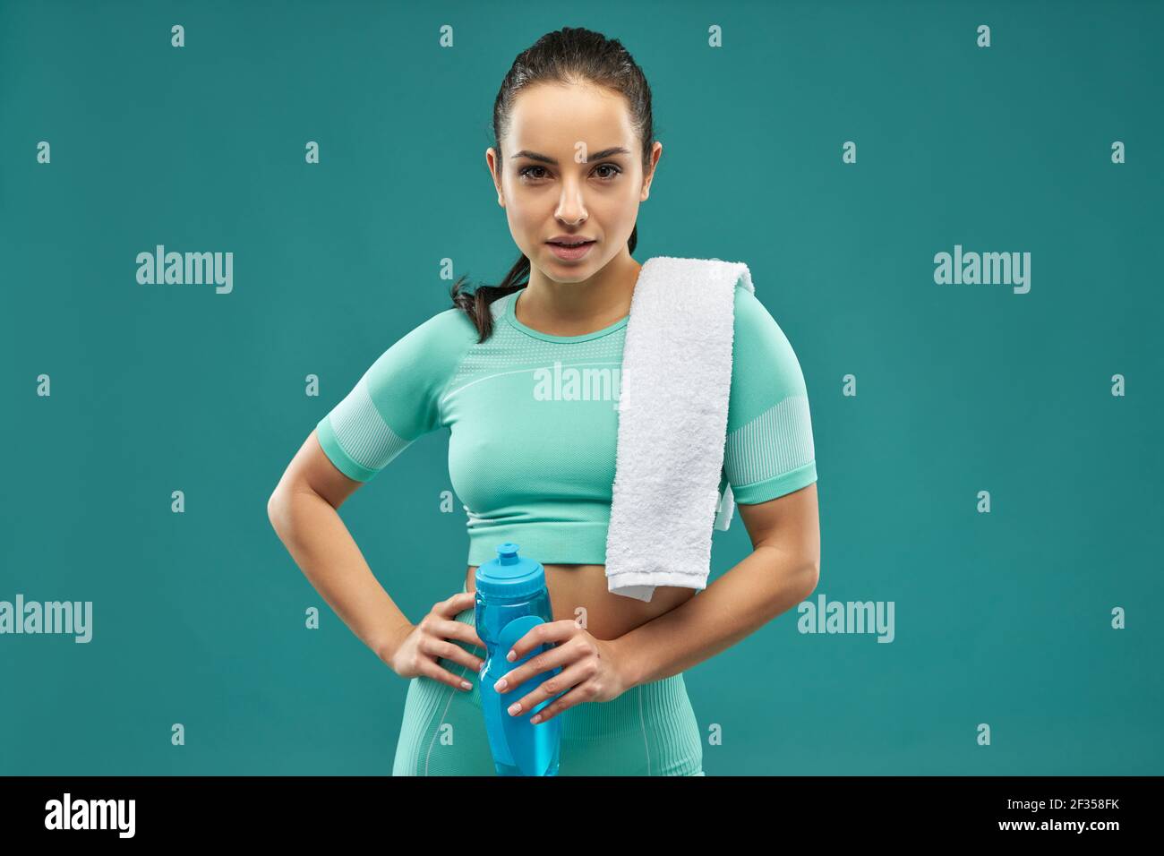 Charmante junge Frau in Sportkleidung hält Flasche Wasser Stockfoto