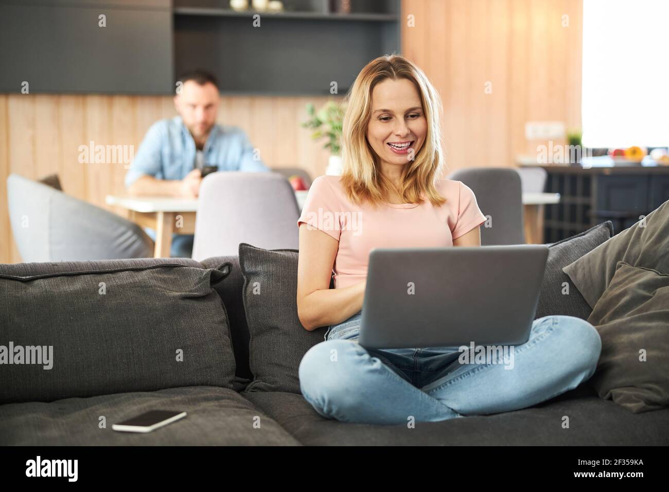 Charmante Frau sitzt auf der Couch und mit Notebook zu Hause Stockfoto