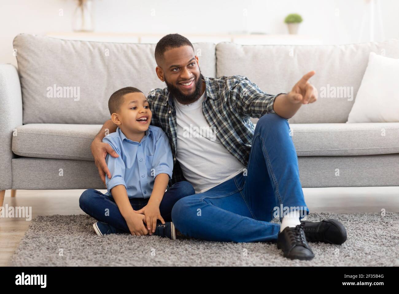 African Vater Und Sohn Umarmt Sitzen Auf Dem Boden Zu Hause Stockfoto