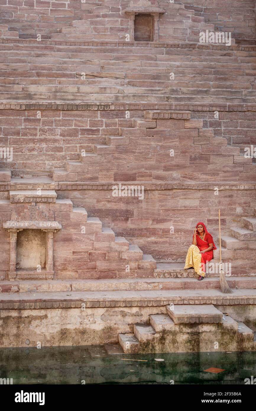 Frau im Sari ruht auf die Stufen am Toorji Ka Jhalara, der Schritt gut, Jodhpur, Rajasthan, Indien Stockfoto
