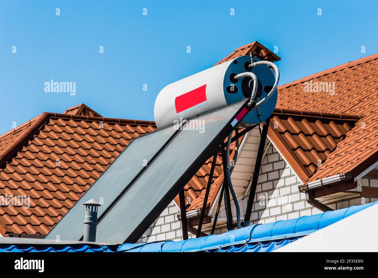 Solarwarmwasserbereiter auf dem Dach eines Gebäudes vor dem Hintergrund des Himmels. Mit Solarenergie Wasser zu erhitzen. Stockfoto