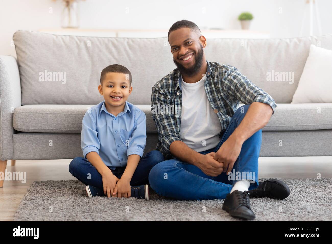 Schwarz Vater Und Sohn Posiert Sitzen Auf Dem Boden Zu Hause Stockfoto