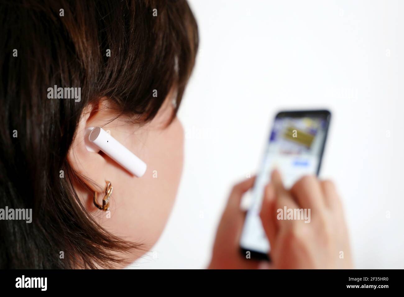 Frau mit schnurlosem Ohrhörer im Ohr. Headset, Musik hören und Video ansehen Konzept Stockfoto