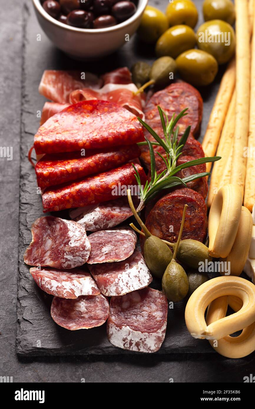 Nahaufnahme des Wurstbretts mit spanischem Jamon, Fuet, Käse und Beeren, Rosmarin Stockfoto