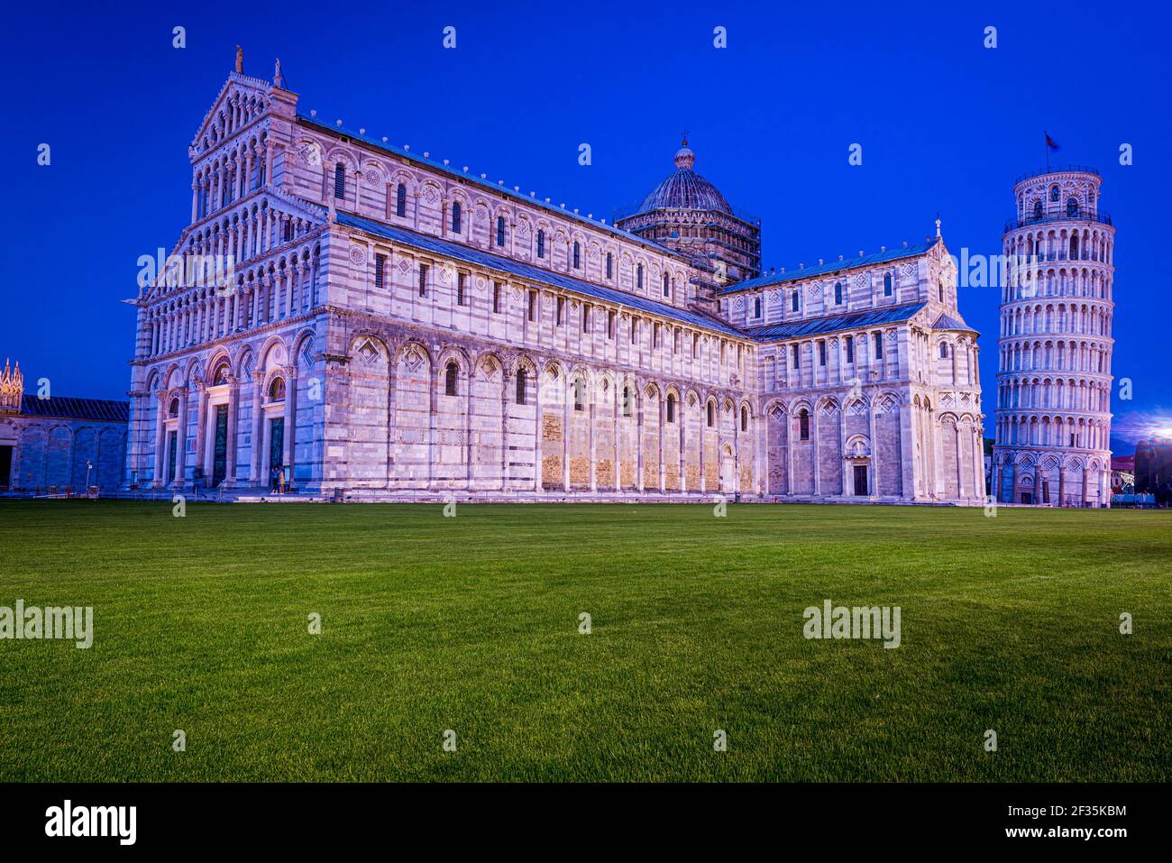 Historische Architekturdenkmäler, die von Reflektoren beleuchtet werden. Schiefer Turm von Pisa und Kathedrale von Pisa auf der Piazza Dei Miracoli, Pisa, Italien. Stockfoto