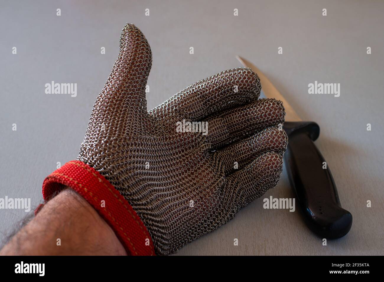 Metall-Schutzhandschuh und Küchenmesser mit selektivem Fokus, für Metzger oder Holzbearbeitung. Stockfoto