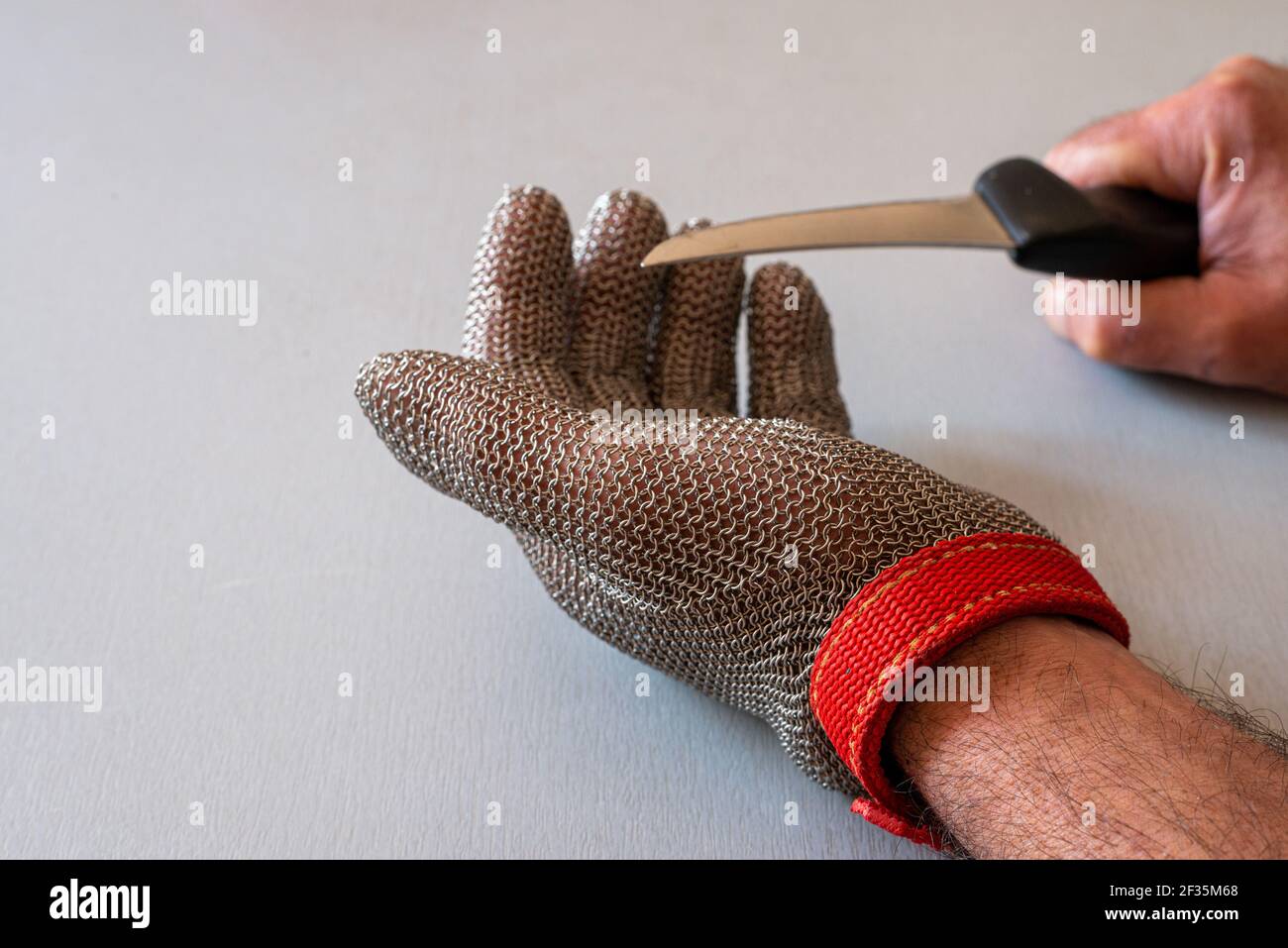 Metall-Schutzhandschuh und Küchenmesser mit selektivem Fokus, für Metzger oder Holzbearbeitung. Stockfoto