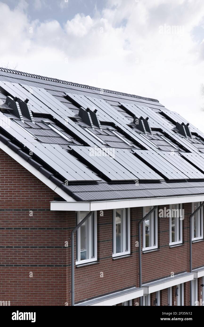 Sonnenkollektoren auf dem Dach eines modernen Neubau-Hauses in Lemmer, Friesland, Niederlande mit blauem bewölktem Himmel montiert. Nachhaltige Energie Stockfoto