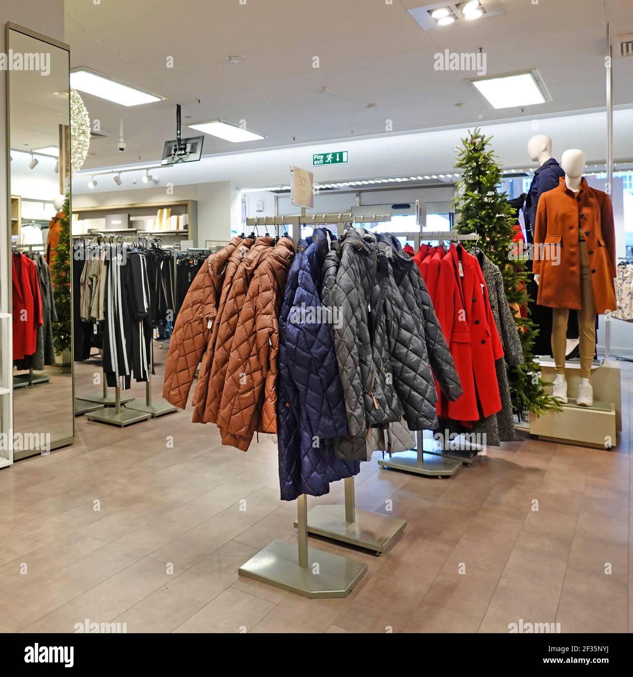 Innenansicht Marks und Spencer Einzelhandel Geschäft Frauen Mode Zeigen Sie M&S Wintermäntel hängen auf Schienen für Inspektion und Kaufen Sie England UK Stockfoto