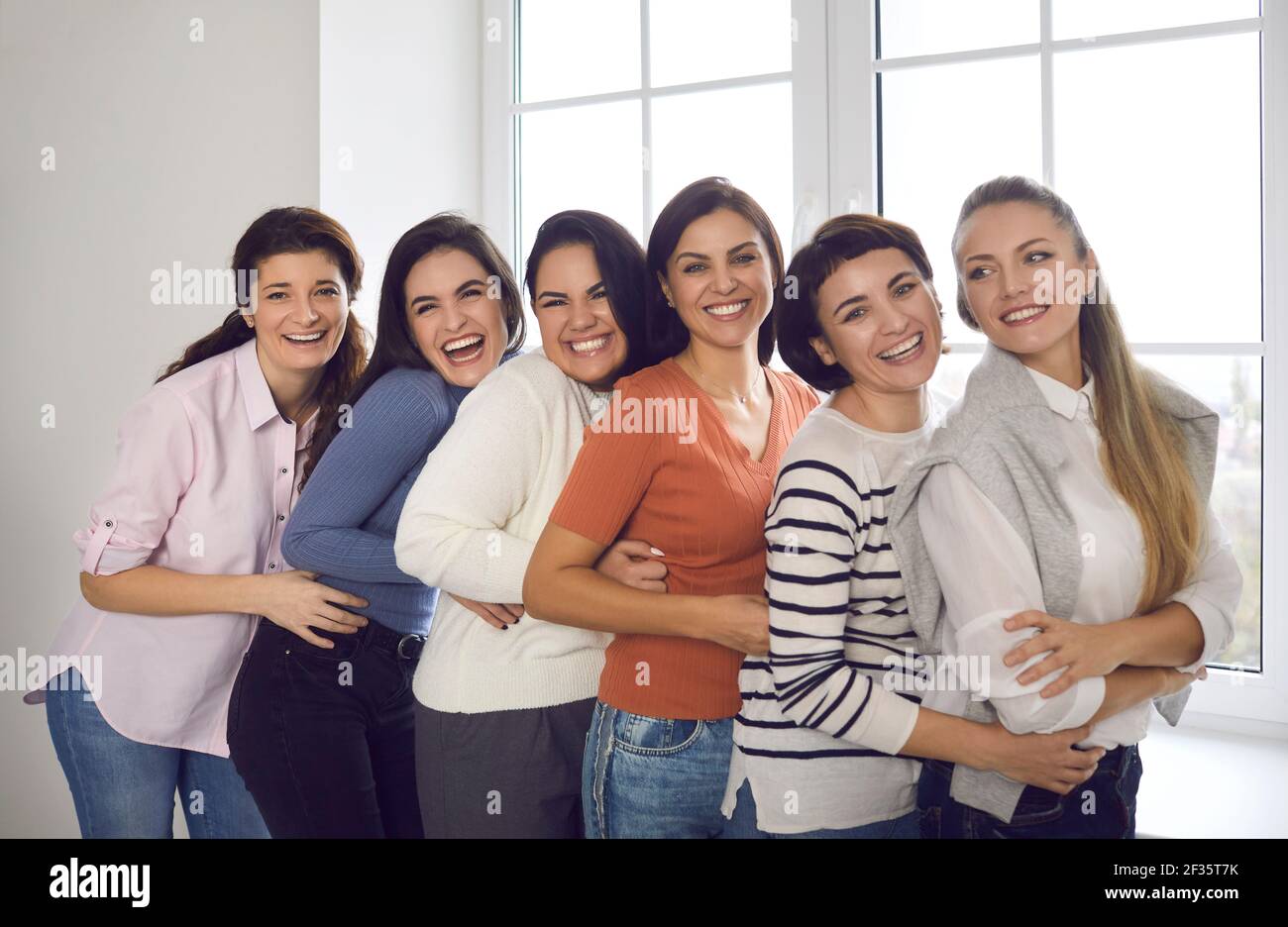 Gruppe von fröhlichen jungen Frauen, die nahe beieinander stehen Und lächelnd auf die Kamera Stockfoto