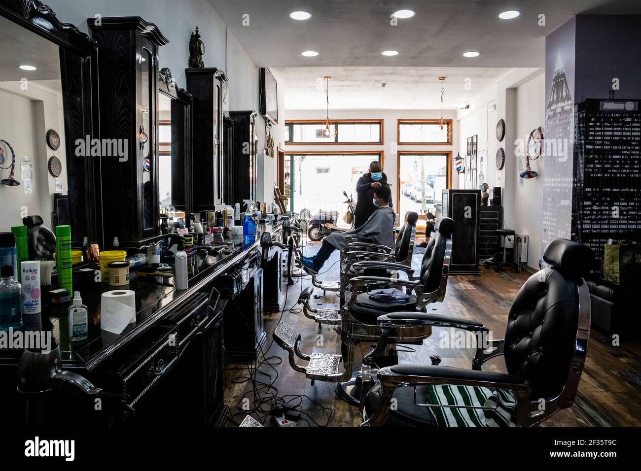 Porto, Portugal. März 2021, 15th. Ein Friseur mit Gesichtsmaske schneidet einem Kunden in einem Friseurladen inmitten der Coronavirus-Krise die Haare kurz.am 11. März wurde das Definationsprogramm angekündigt und wird schrittweise in 4 Teile aufgeteilt, in einer Zeit, die bis Ostern geht, und kann Rückschläge haben. Ab diesem Montag mit der Eröffnung von Kindergärten, 1st Zyklus, Friseure, Manikuristen, Immobilien, Buchhandlungen und Wicket-Kaffee-Service. Kredit: SOPA Images Limited/Alamy Live Nachrichten Stockfoto