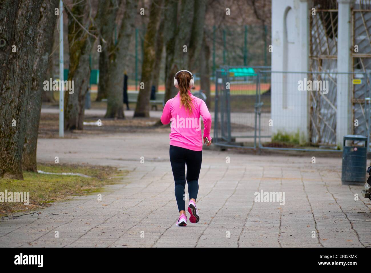 Blonde Mädchen laufen oder joggen allein mit Kopfhörer oder Headset Im Park in der Stadt Stockfoto