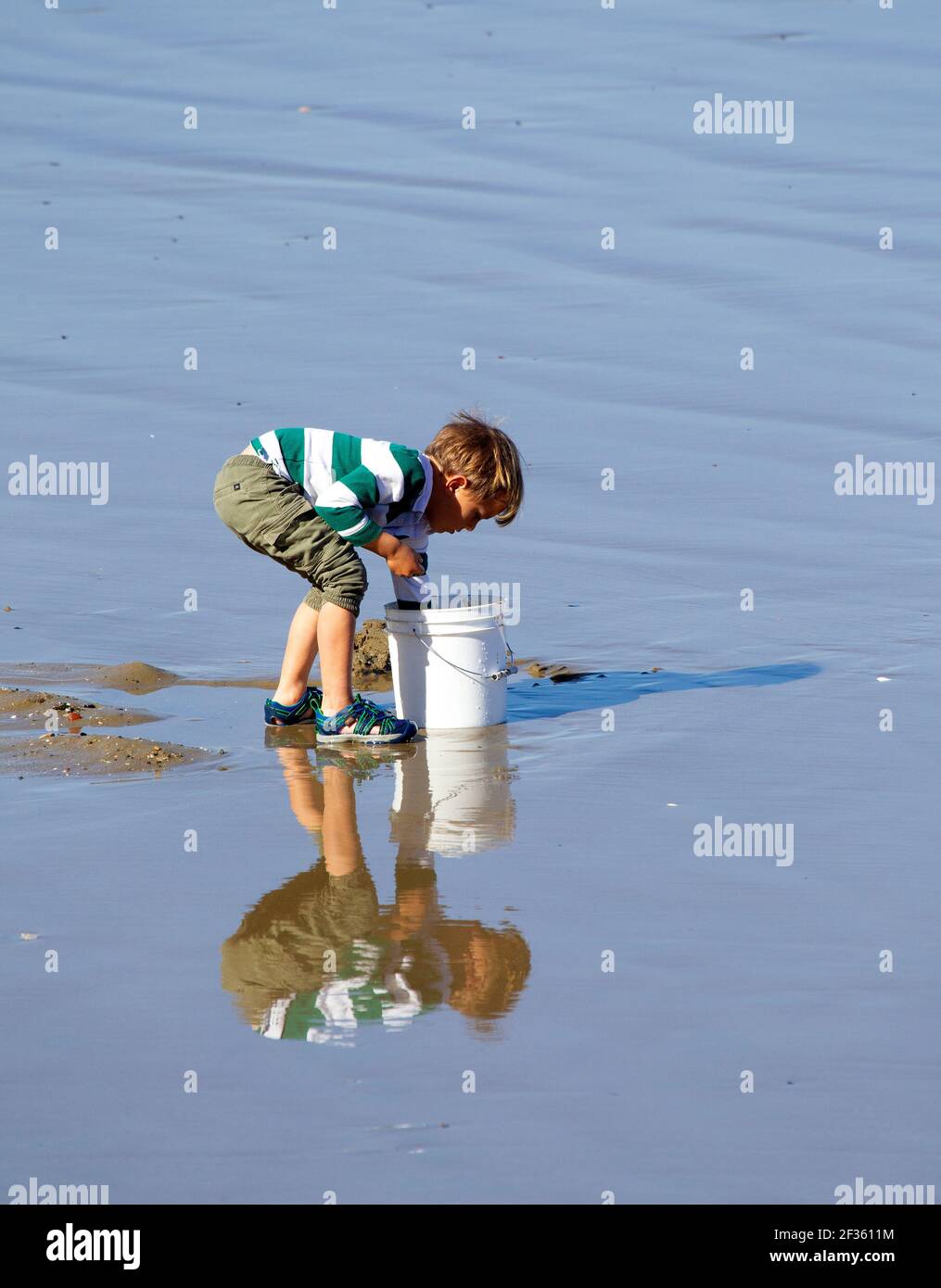 Kleiner Junge Reflexion in nassem Sand Stockfoto