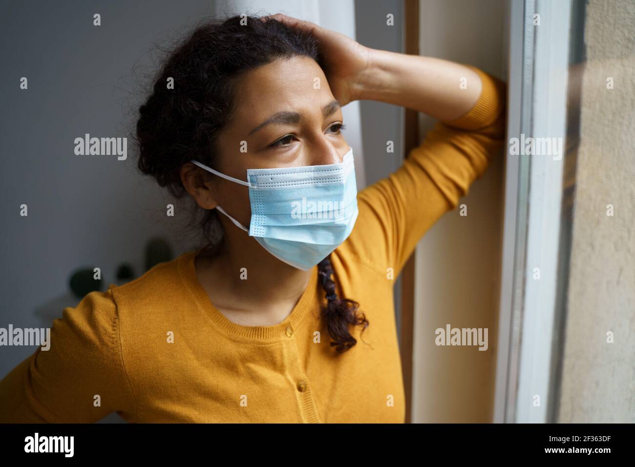 Besorgte schwarze Frau, die aus dem Fenster schaute Stockfoto