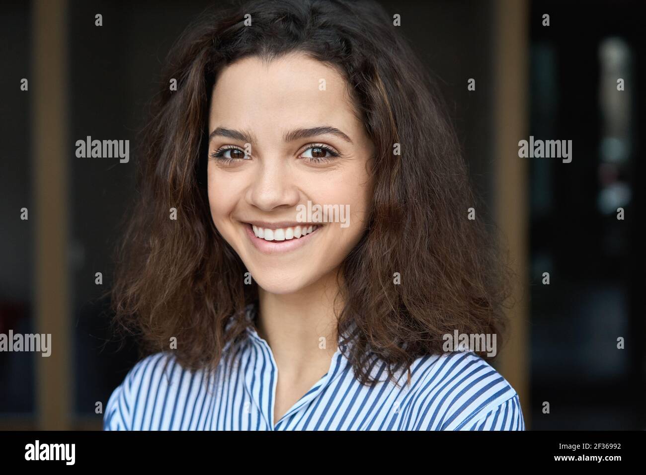 Schöne glückliche hispanische junge Erwachsene 20s Frau Blick auf Kamera, Kopfschuss. Stockfoto