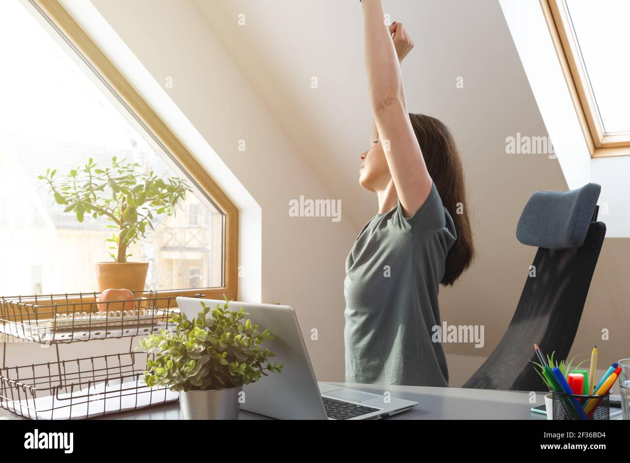 Frau streckt ihre Hände auf dem Schreibtisch in einer Pause von der Arbeit im Home Office. Bewegung und gesundes Wohnkonzept. Stockfoto