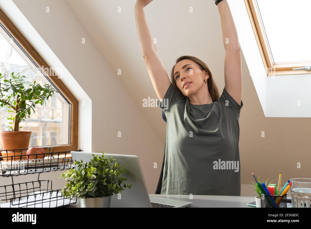 Frau streckt ihre Hände auf dem Schreibtisch in einer Pause von der Arbeit im Home Office. Bewegung und gesundes Wohnkonzept. Stockfoto