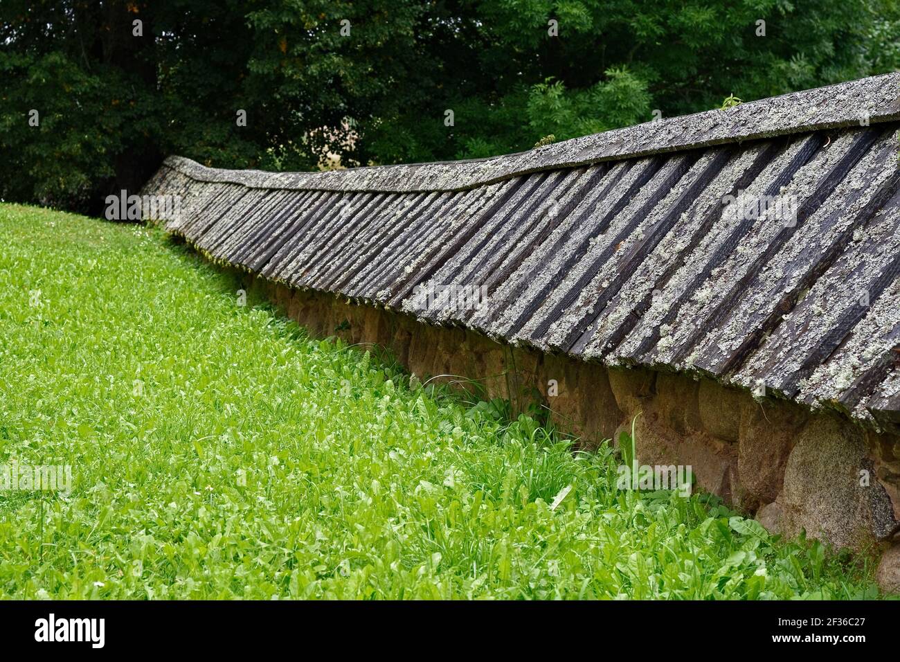 Alte Steinhecke mit einem Dach aus grauen Moosplanken. Stockfoto