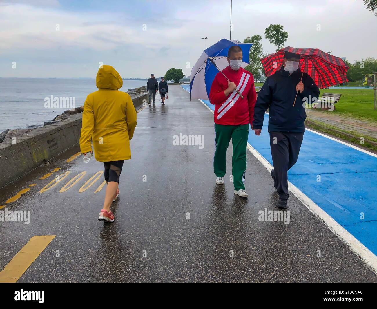 Istanbul, Türkei - 1. Juni 2020: Neue Normalität. Menschen zu Fuß mit Covid-19 schützende medizinische Gesichtsmaske Konzept. Morgensport an einem regnerischen Tag. Zwei Männer Stockfoto